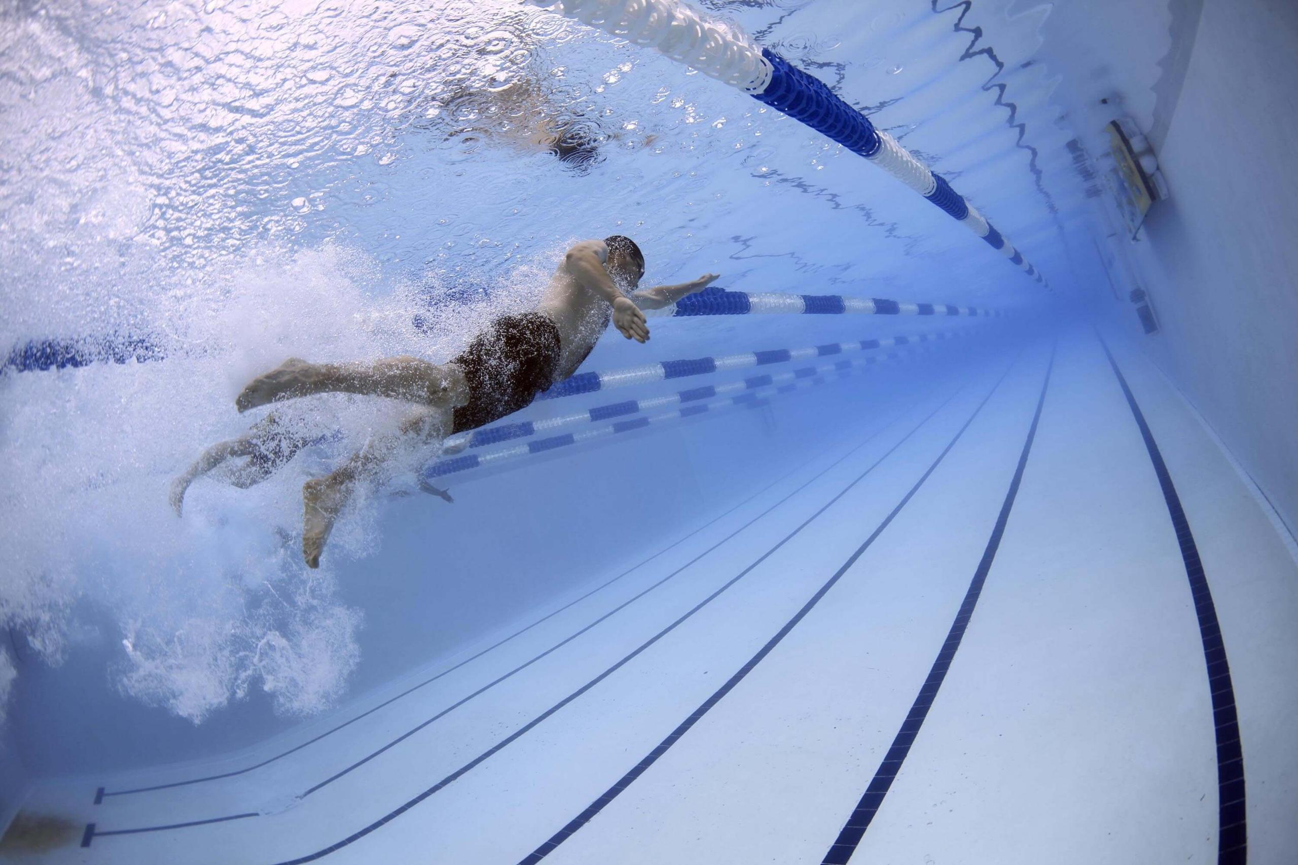 Underwater view of a swimmer streamlining beneath the surface of an indoor pool